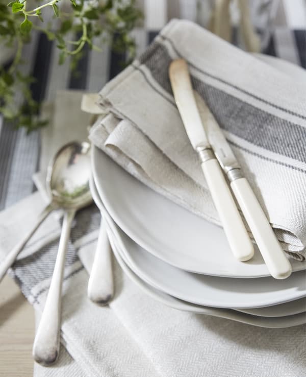 Serviettes de table en coton de couleurs neutres et couteaux déposés sur des assiettes blanches