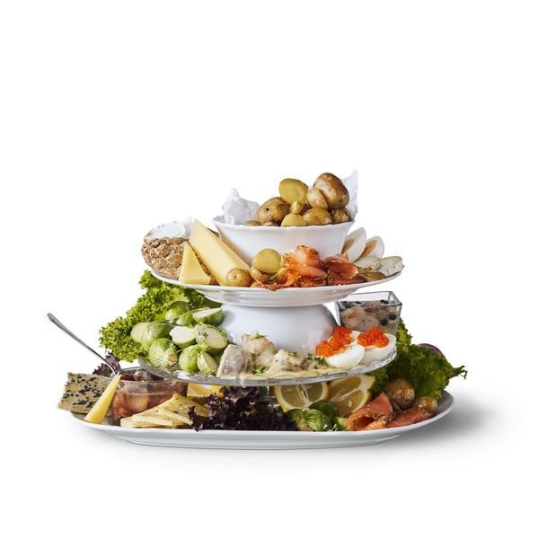 Serving dishes stacked with cheese, crispbread, and assorted veggies on them. 