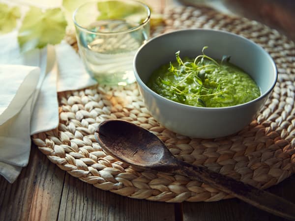 Set de table SOARÉ sur lequel sont posés un bol de soupe aux légumes, une cuillère en bois, une serviette et un verre d’eau.