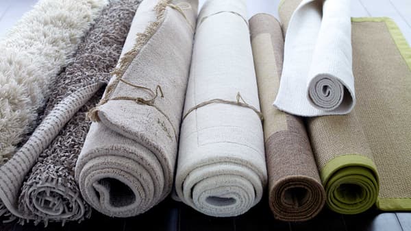Several different carpets are rolled up on the floor.