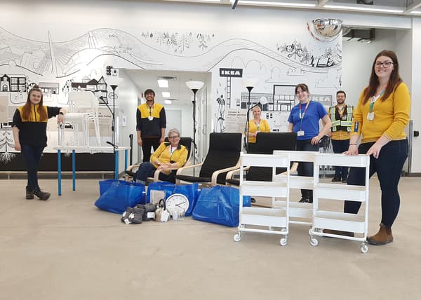 Several IKEA coworkers beside white carts and bags of supplies for charity.