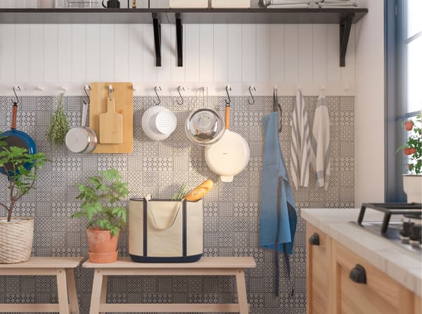 Several IKEA KUBBIS white racks with 7 hooks mounted on a wall and used to hang kitchen utensils.
