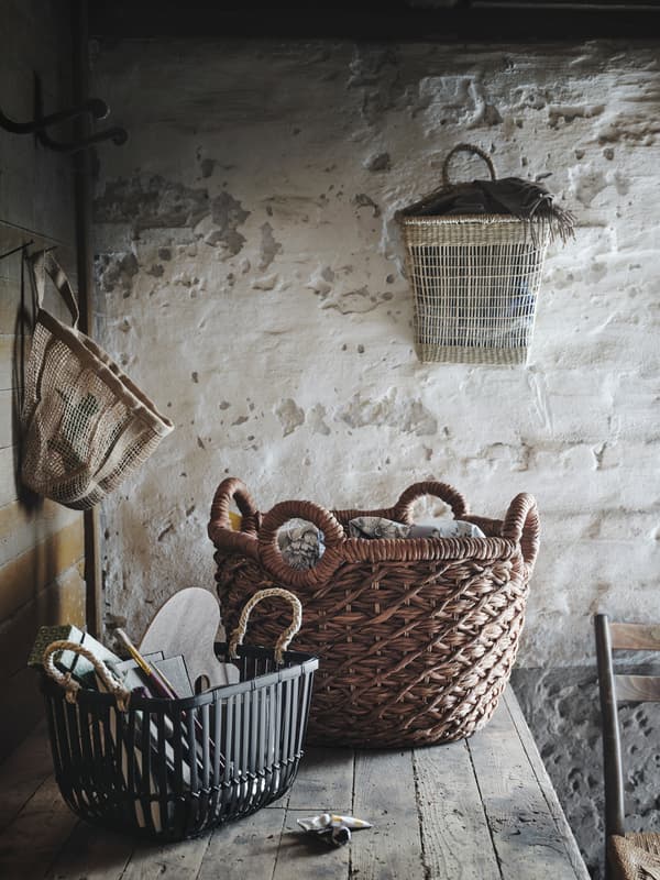 Several LUSTIGKURRE baskets made in natural materials like nipa palm, seagrass and bamboo hanging or standing in a shed.