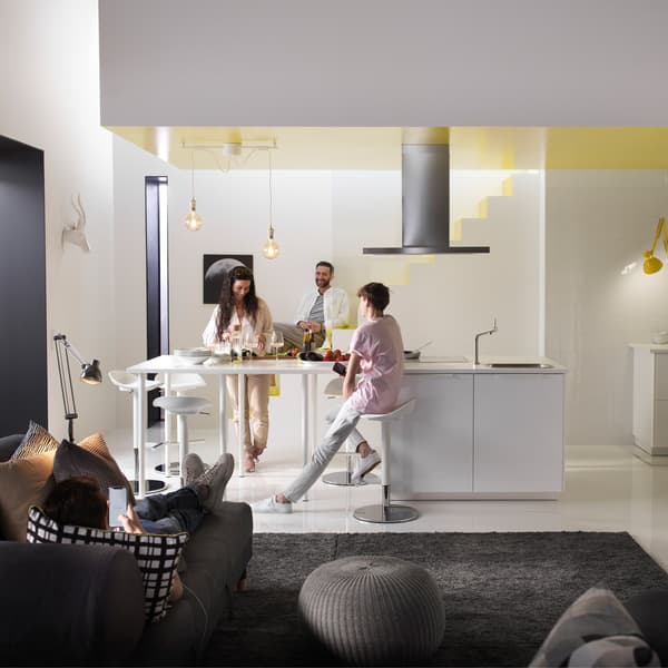 Several people seated and standing around an open living space, with the kitchen area the main focus.