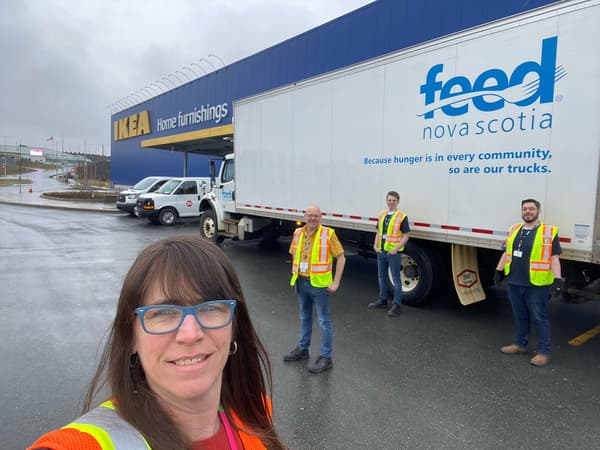 Several smiling IKEA employees next to a truck at an IKEA store reading 'Feed Nova Scotia'.