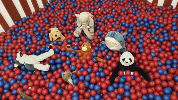 Several soft toys are sitting in the ball pit in the IKEA Småland play area. 