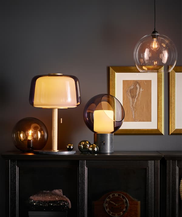 Several table lamps and a pendant lamp in rounded shapes, all casting a warm, golden light.