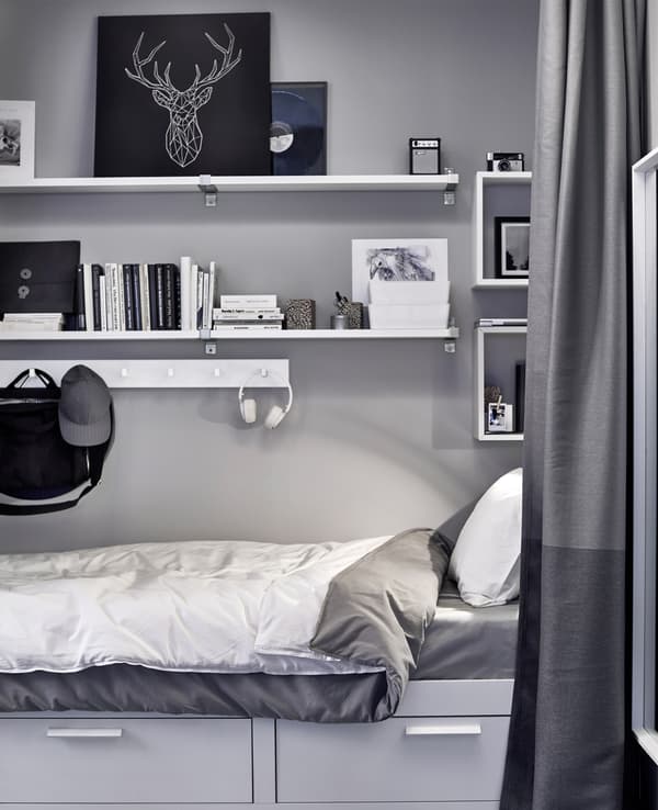 Shelving and hooks store artwork, books, boxes and more above a bed.