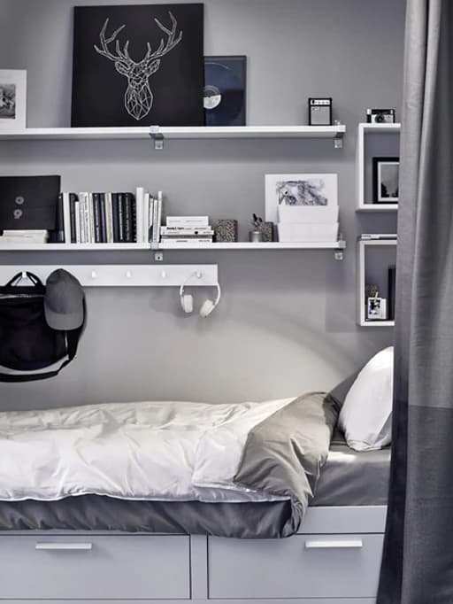 Shelving and hooks store artwork, books, boxes and more above a bed.