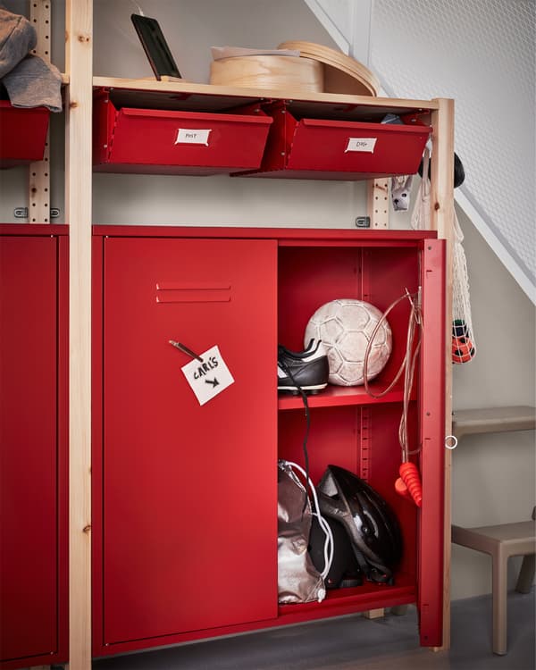 Shelving unit in pine with red drawers and cabinets. KUNGSFORS magnetic clip with a note is placed on one of the doors.