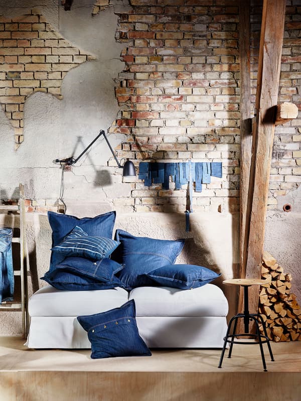 Shown piled on a sofa, square denim SISSIL cushion covers come in two sizes with details like buttons and jean-like seams.