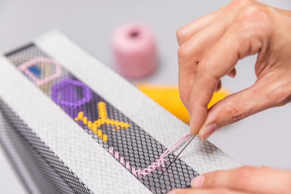 Sie macht in den Ordner Buchstaben mit den Fäden in 3 verschiedenen Farben.