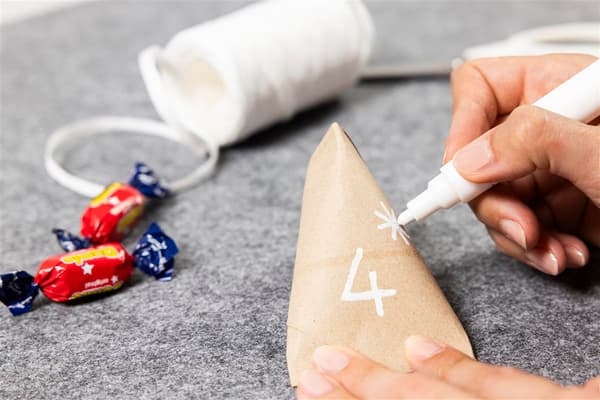 Sie schreibt mit einem weißen Stift die Zahl 4 darauf und einen kleinen Stern.