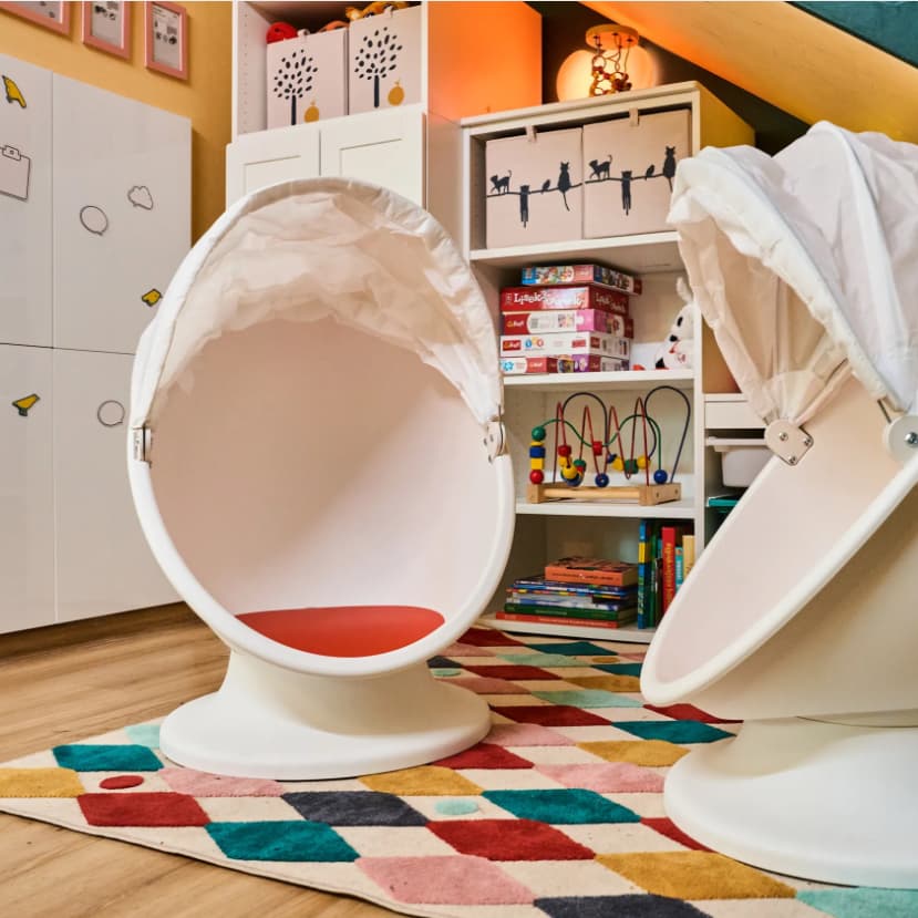 Siedzkio dla dziecka w kształce jajka z rozwijanym daszkiem na kolorowycm dywanie