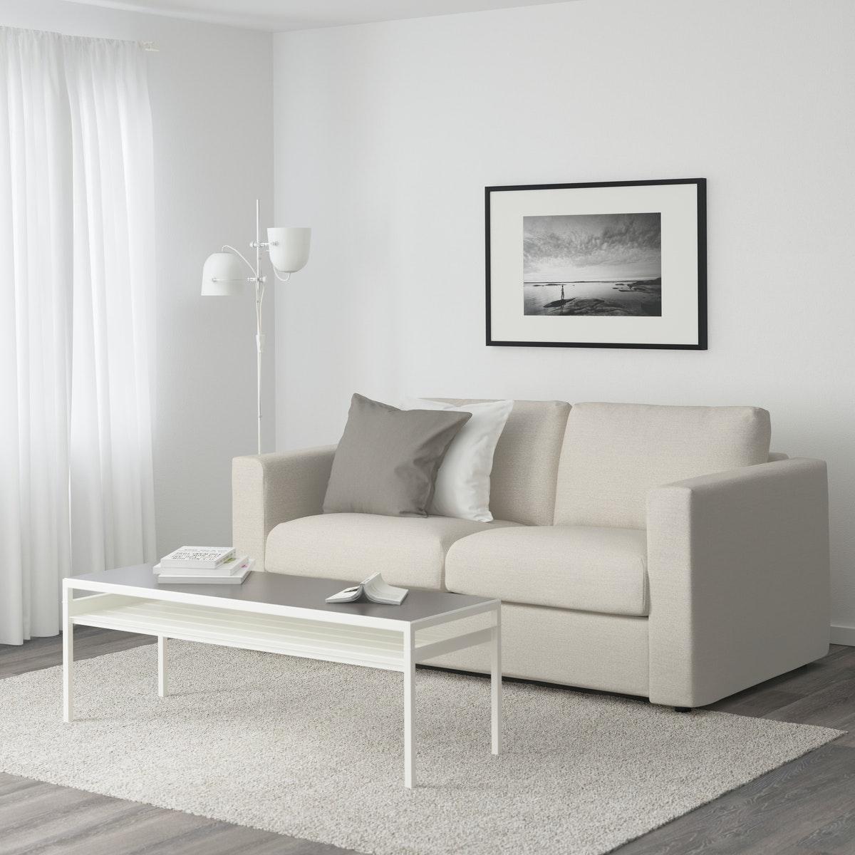 Sillón VIMLE color blanco junto a una lámpara de pie blanca y una mesa de centro blanca.