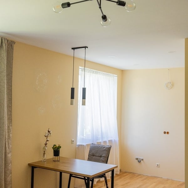 Simple dining space with wooden table, chair and ceiling lights in a newly renovated interior
