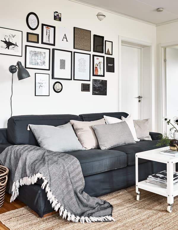 Simple, framed artwork creates a gallery wall above a grey sofa in a living room.