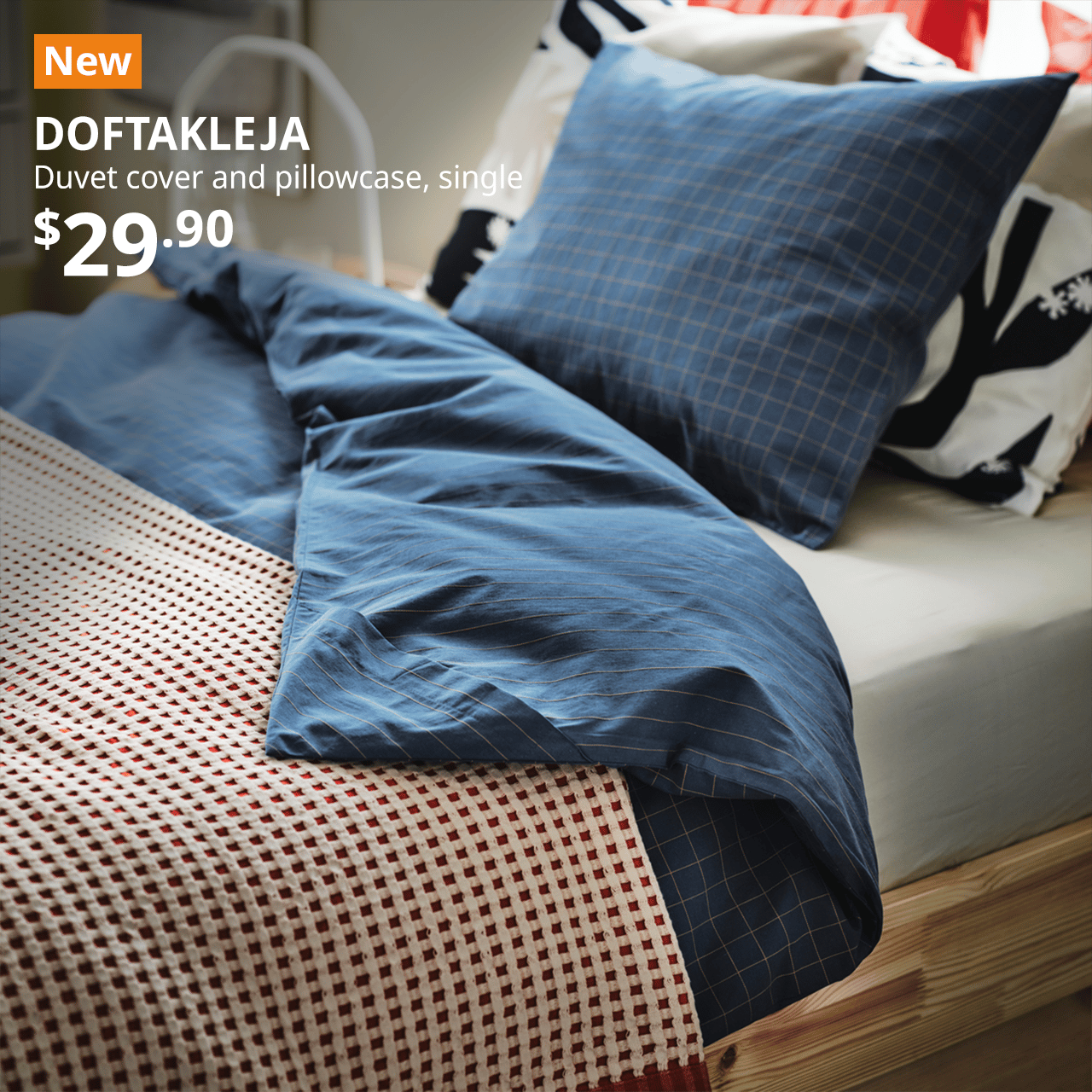 Single sized bed frame in the bedroom with DOKTAFLEJA dark blue checkered duvet cover and pillow case on top. Top left hand corner shows a orange tag with the word NEW on it, and black text below that reads: DOKTAFLEJA, Duvet cover and pillowcase, single. Priced at $29.90.