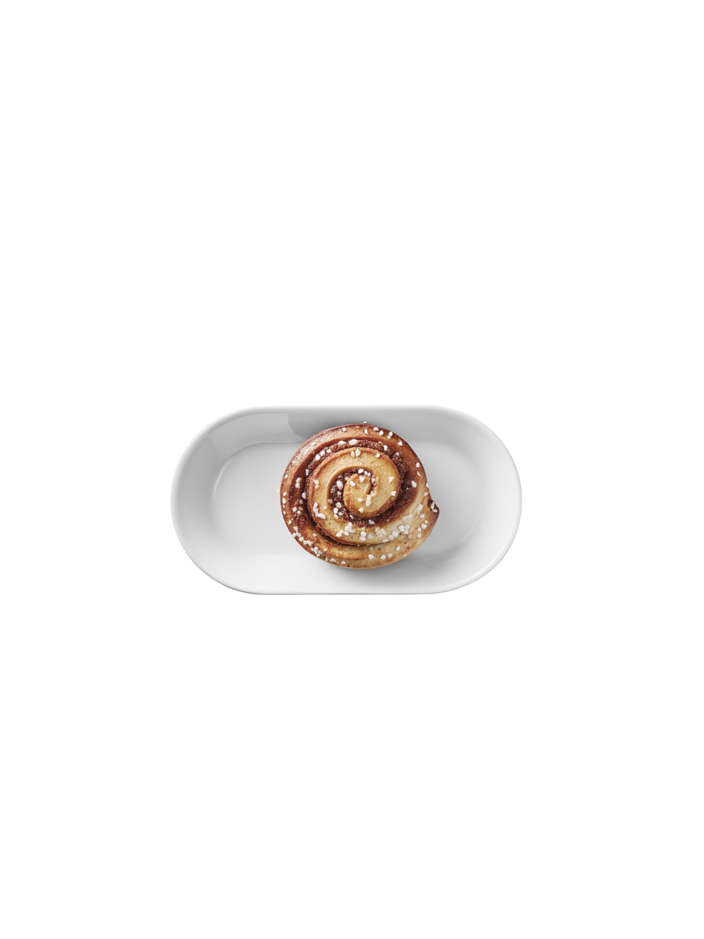 Single Swedish cinnamon bun with pearl sugar on a white oval plate.