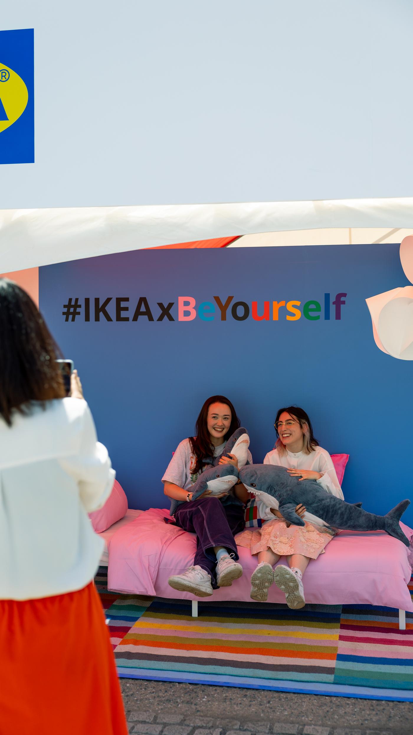 Sitting on a bed, holding a shark plush toy, and taking a photo.