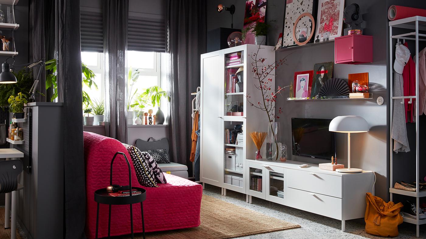 Siv životni prostor s IKEA PLATSA belim kombinovanim odlaganjem za audio-video i roze sofom.