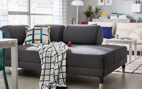 Siva sofa u dnevnoj sobi s tekstilima s grafičkim šarama.