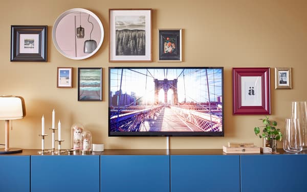 Six blue BESTÅ cabinets, with a television and gallery wall around it.