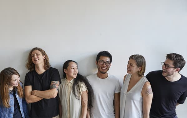 Six Nest residents pose infront of a white wall.