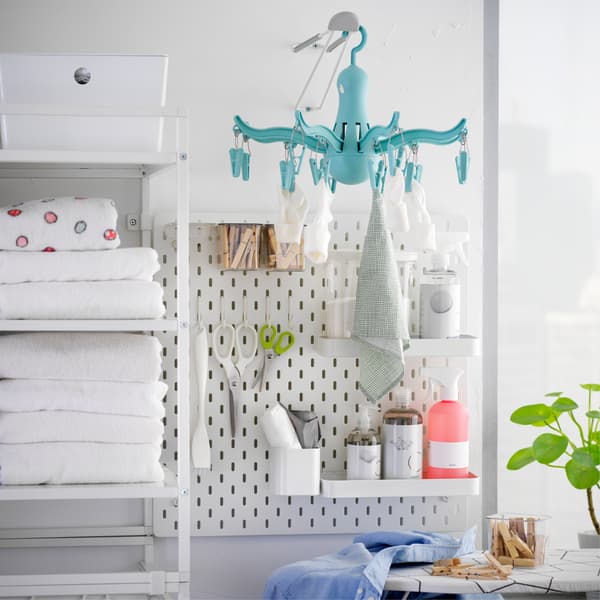 SKÅDIS white pegboard combination with hooks and shelves holding clothes pegs, bathroom articles and smaller laundry items.