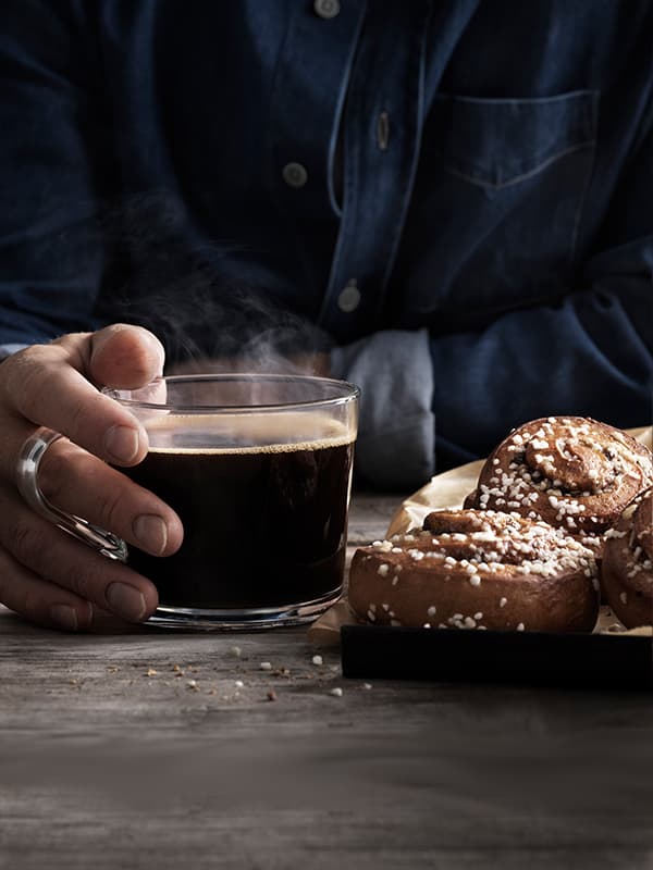 Skleněný šálek kávy a dva skořicoví šneci