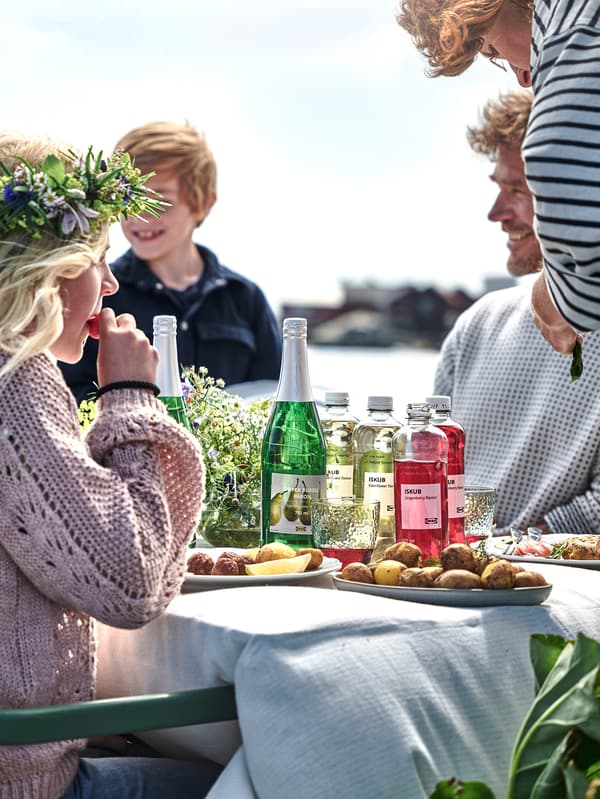 Skupinka lidí kolem stolu plného midsommarových dobrot.