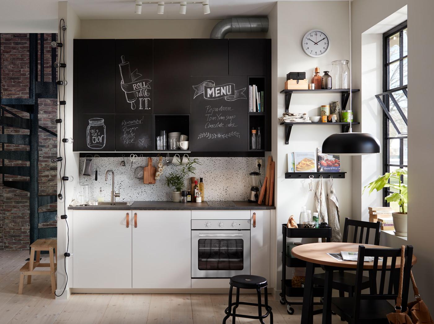 Small black and white kitchen with chalk doors inscribed with messages.