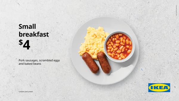 Small breakfast. White plate on concrete background with scrambled egg, 2 sausages, and small bowl of baked beans, for $4