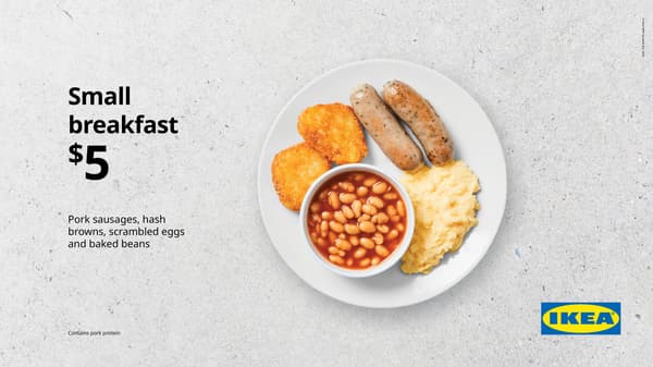 Small breakfast. White plate on concrete background with scrambled egg, 2 sausages, and small bowl of baked beans