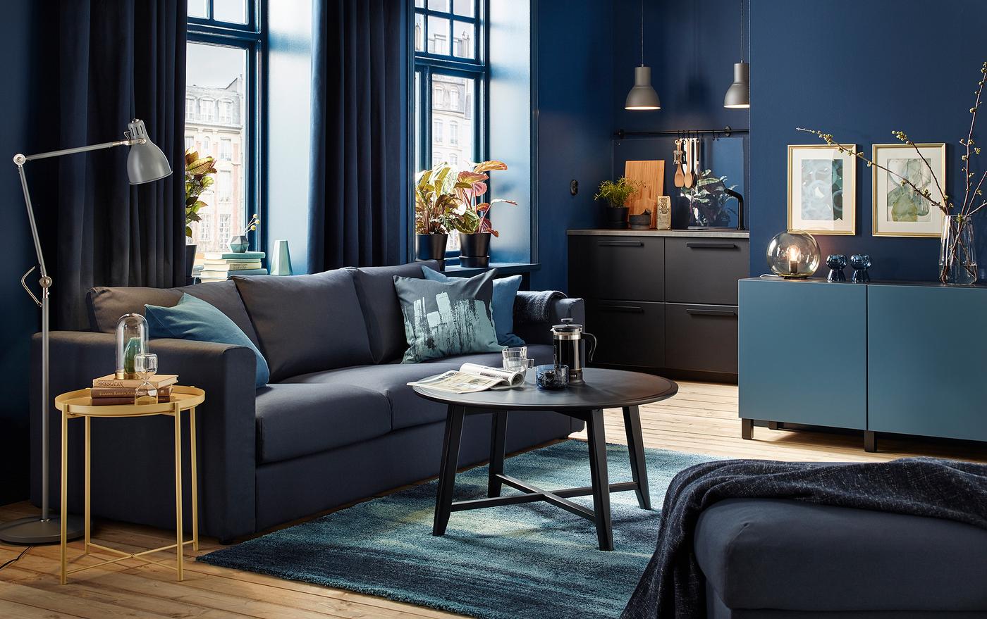 Small dark blue living room with black-blue sofa and black round coffee table.