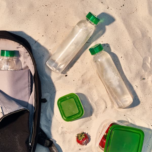 Small food storage containers and water bottles are unpacked from a backpack.