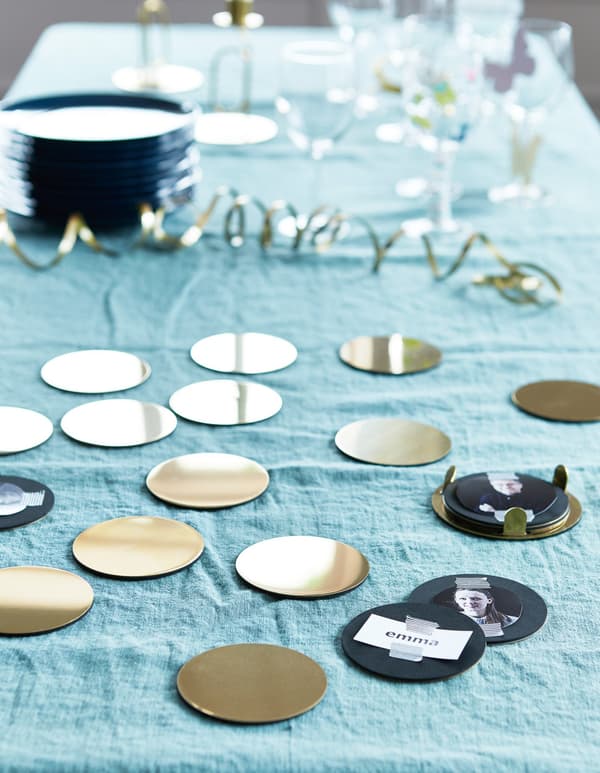 Small golden and black discs decorated with photos and name tags for a party game.