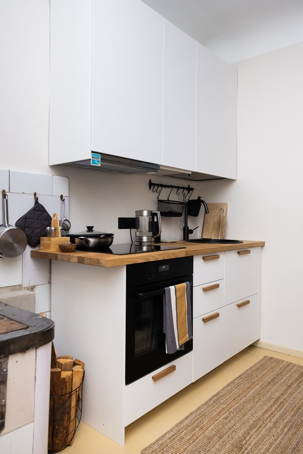 Small kitchen with closed cabinets and an open wall shelf for additional storage.