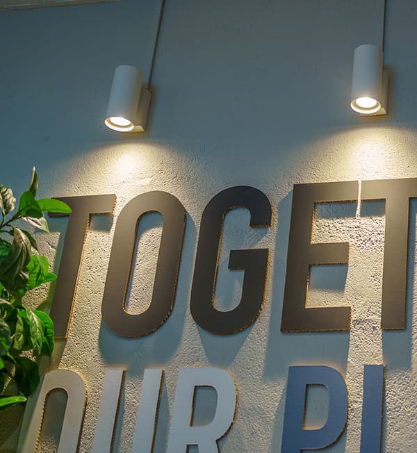 Small lights shining on 3D letters on a wall.