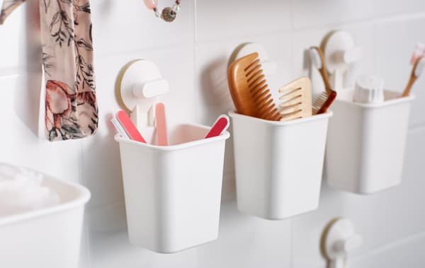 Small plastic baskets are attached to the bathroom wall with suction cups and hold toiletries and accessories.