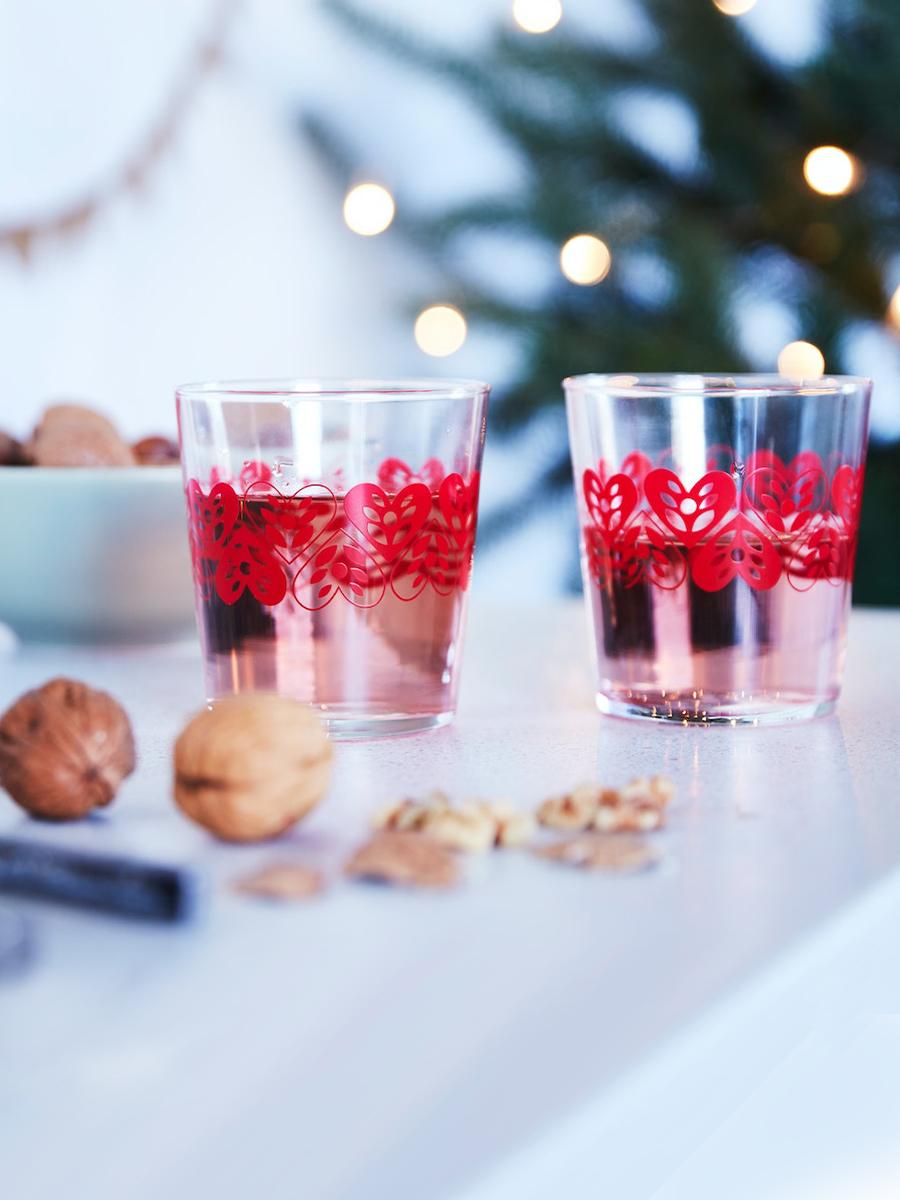 Small VINTERFINT 2022 glasses with red heart patterns are placed on a table beside a bowl of nuts.