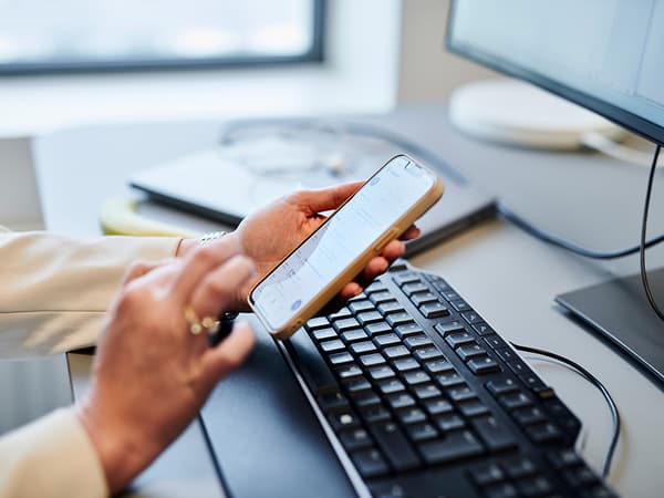 Smartphone, teclado y monitor en un espacio de trabajo moderno y organizado.