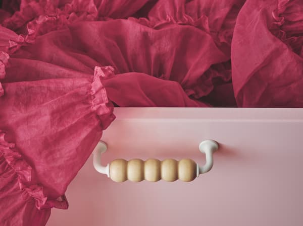 SMÅSTAD fiókos elem különleges fa fogantyúval, egy világosrózsaszín fiókelőlapra szerelve, a fiókból egy élénk pink tüllszoknya lóg ki..