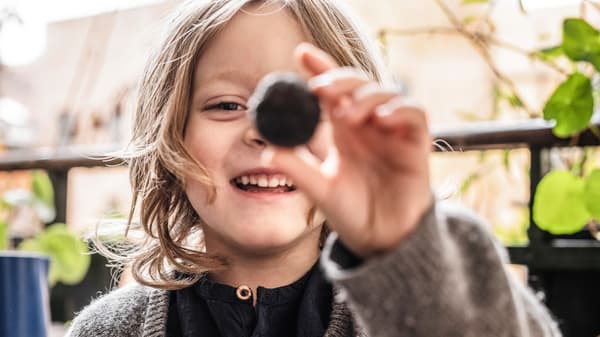 Smiling child with a round object in its hands.