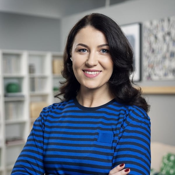 Smiling woman in striped blue shirt standing in living room.