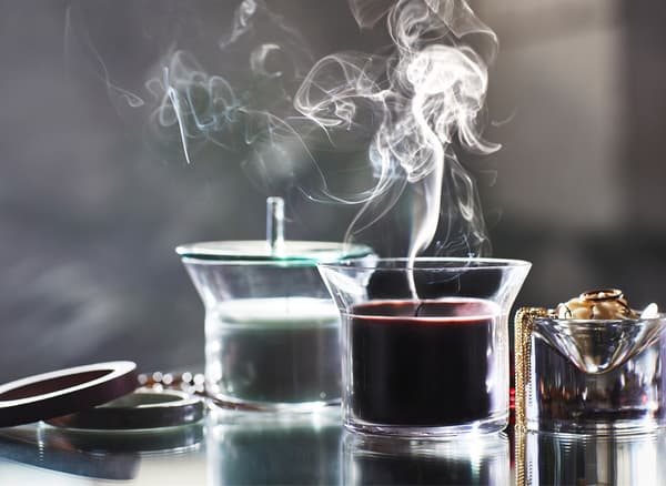 Smoke rising from a candle in a glass holder.