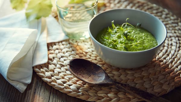 SOARÉ-tabletilla kulhollinen kasviskeittoa, puinen lusikka, lautasliina ja lasi vettä.