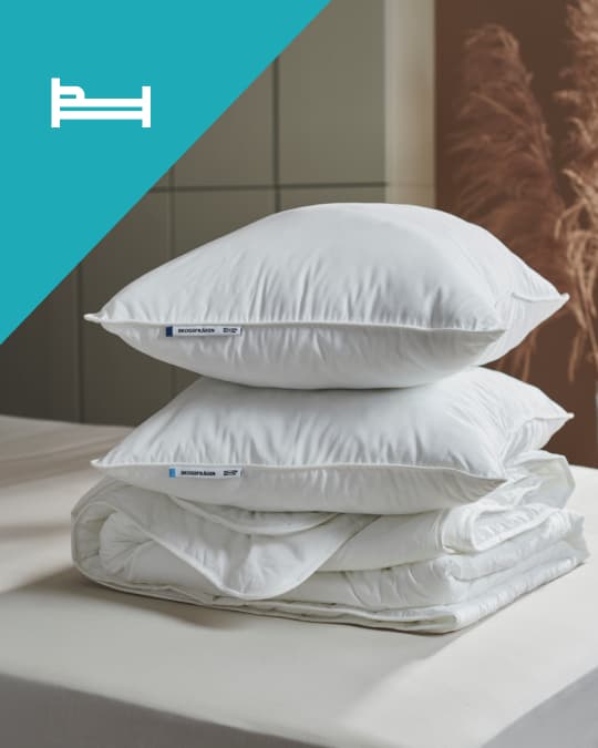 Sobre una cama un plumón y dos almohadas IKEA.