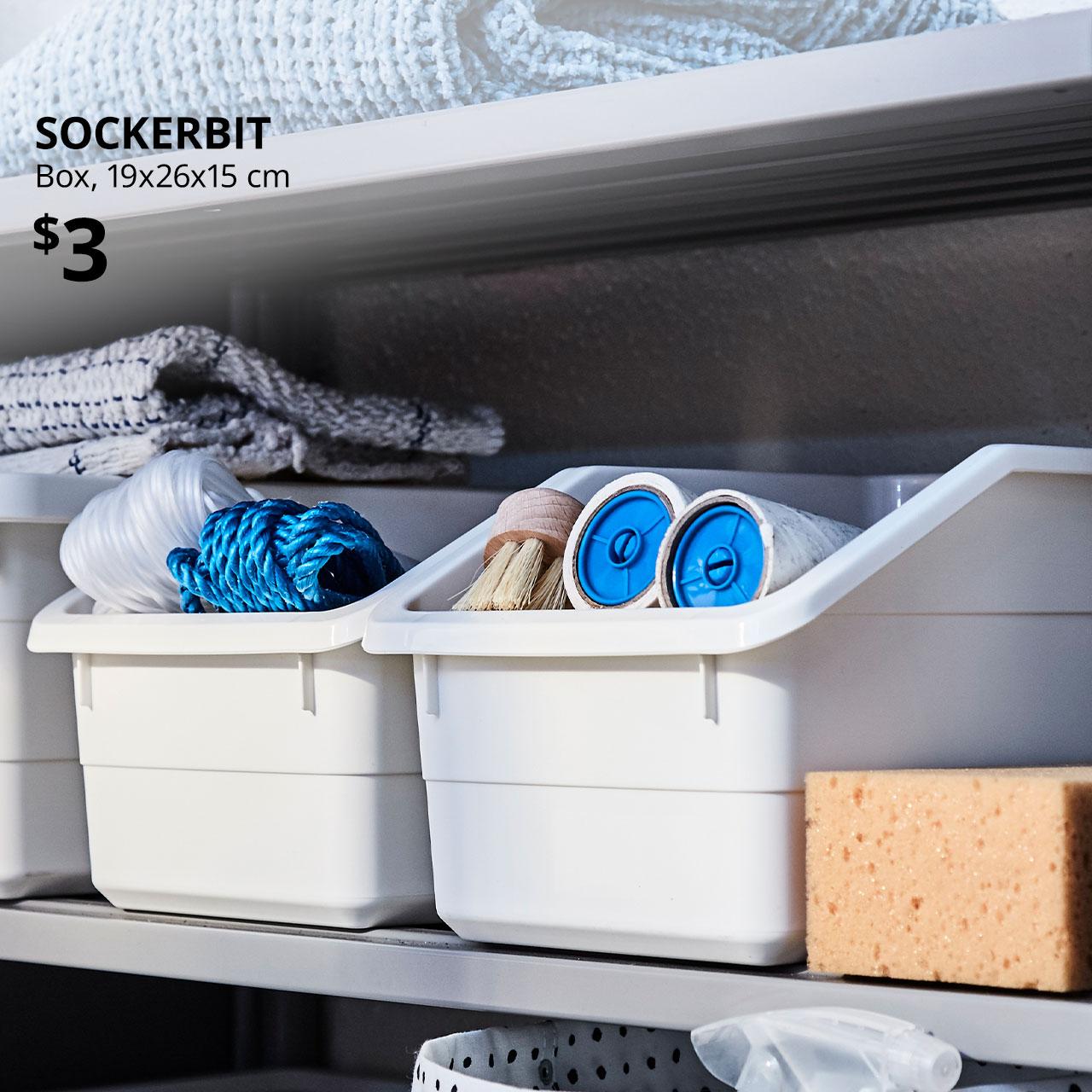 SOCKERBIT in white with home essentials like BÄSTIS lint rollers. Text on image reads "SOCKERBIT, Box, 19x26x15 cm. Price at $3"