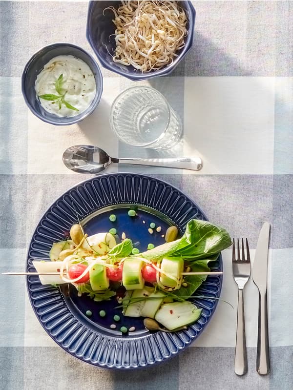 Sötétkék STRIMMIG étkészlet, alatta kockás asztali futó.